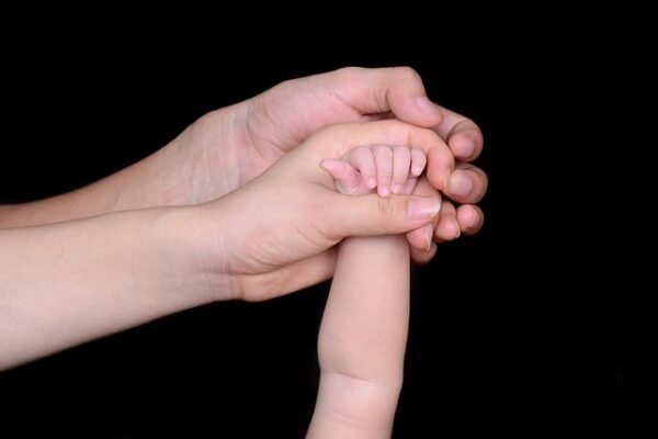 Baby hand holding parent’s, showing child support